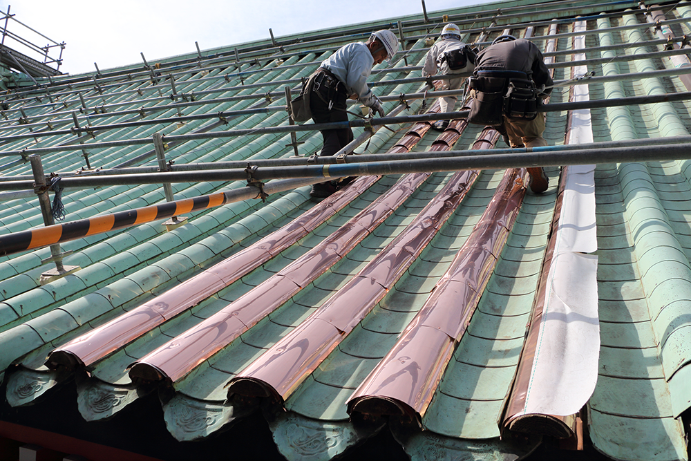銅板屋根施工風景：既存緑青銅板の下に、新規銅板を葺いて銅板屋根を二重化