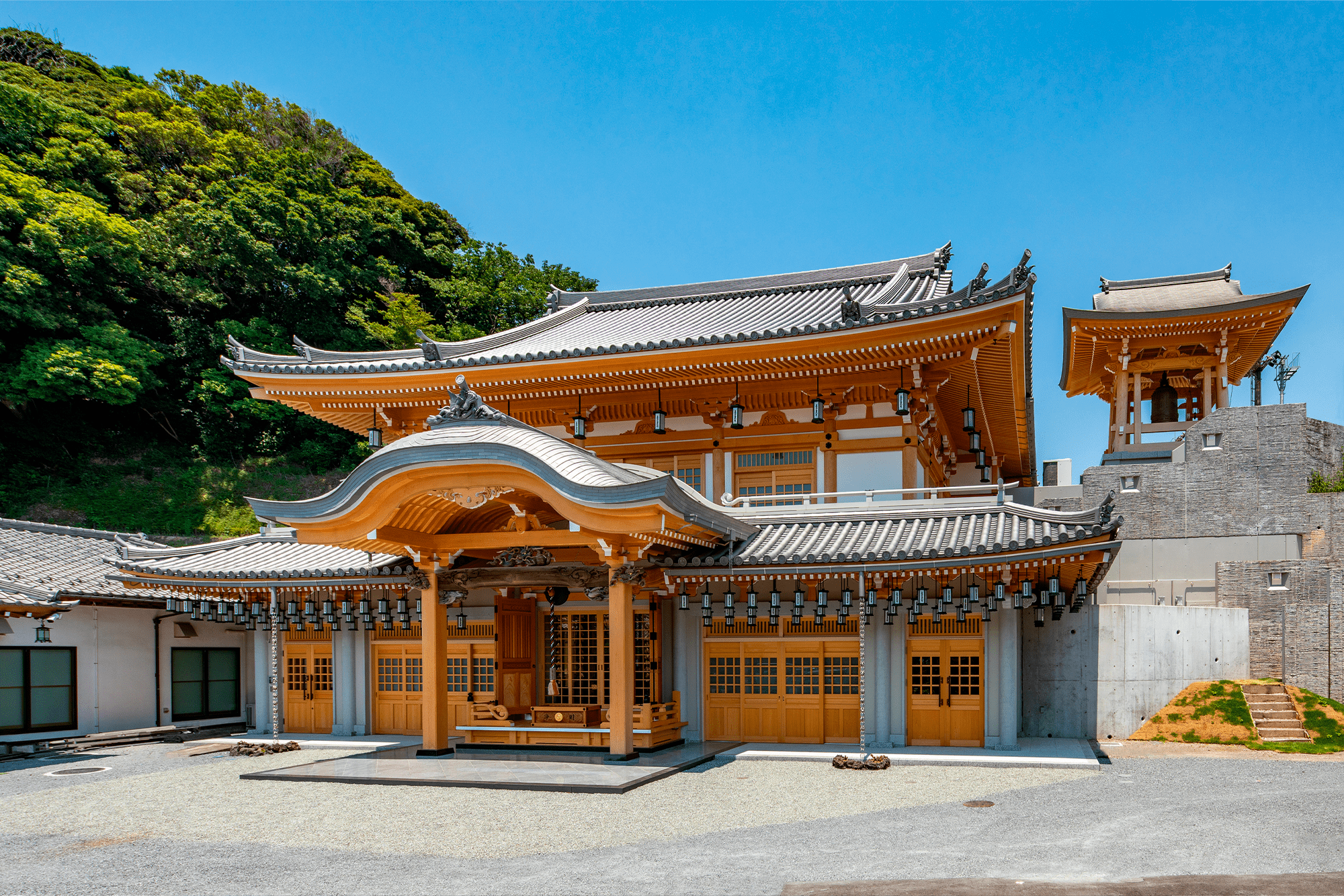 建物が背後の高台の土留めを兼ねることで見え掛り高さを稼ぎ、さらに下階のRC造と上階の伝統木造は、木割に基づく調和した重層形式の意匠とすることで一体感のある外観としている